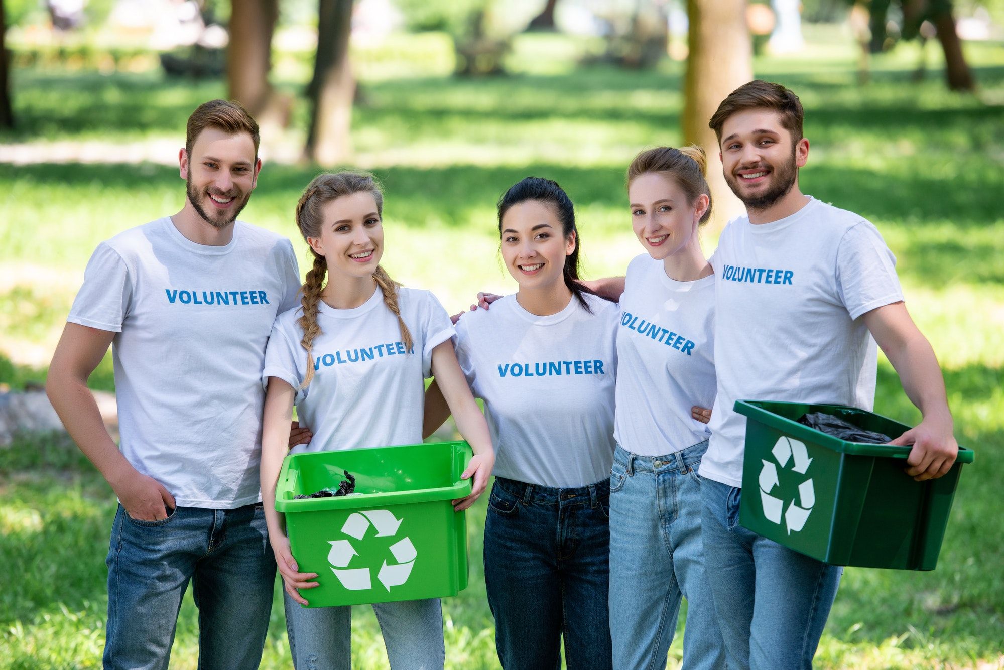 young-volunteers-with-green-recycling-boxes-for-trash-standing-in-park-1